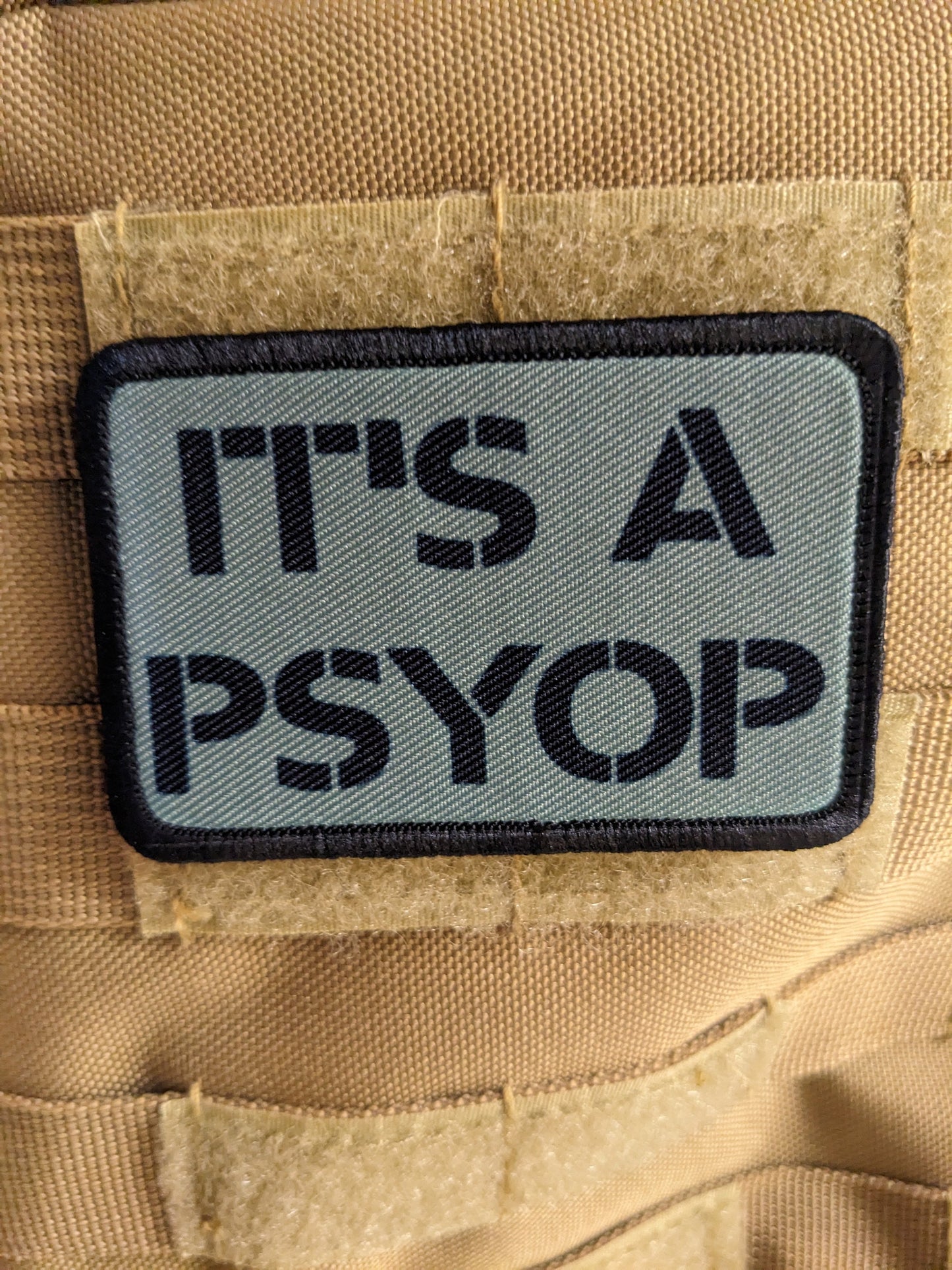 It's a Psyop conspiracy joke gray 2"x3" morale patch with hook and loop backing