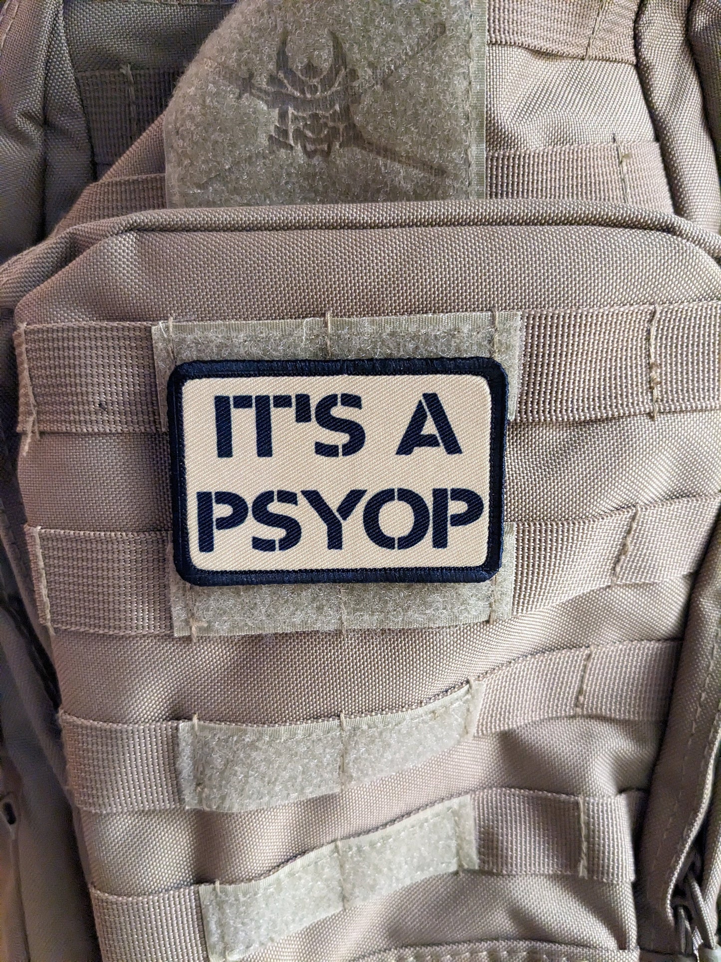 It's a Psyop conspiracy joke tan 2"x3" morale patch with hook and loop backing